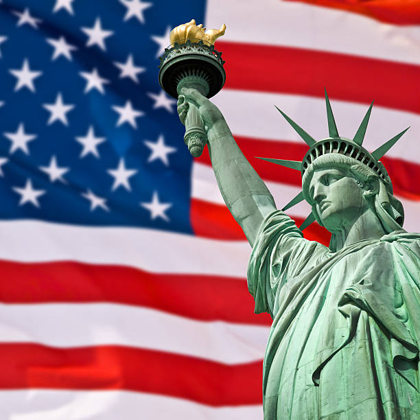 statue of liberty, sunny sky and usa flag background